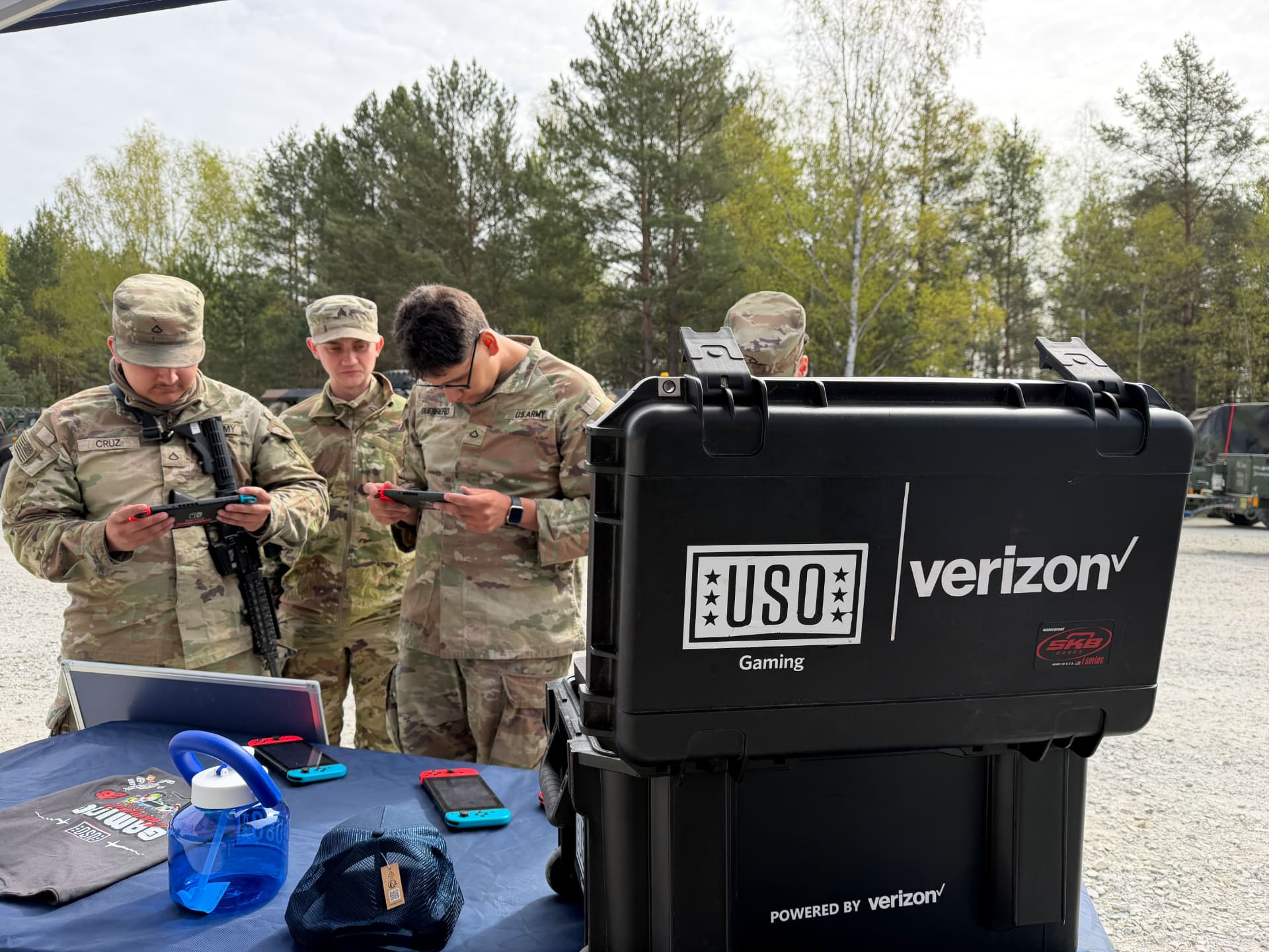 Soldiers playing handheld games beside a USO mobile gaming kit.